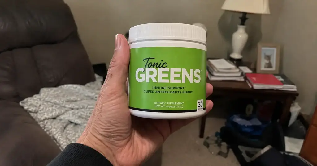 Hand holding Tonic Greens supplement