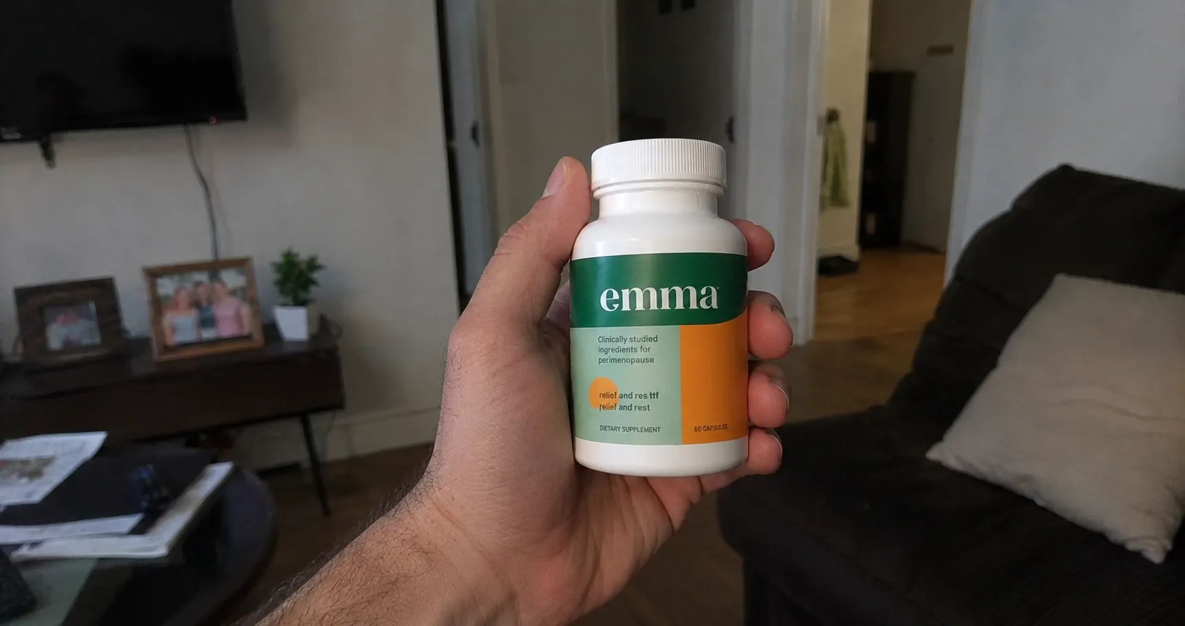Hand holding Emma Relief supplement bottle