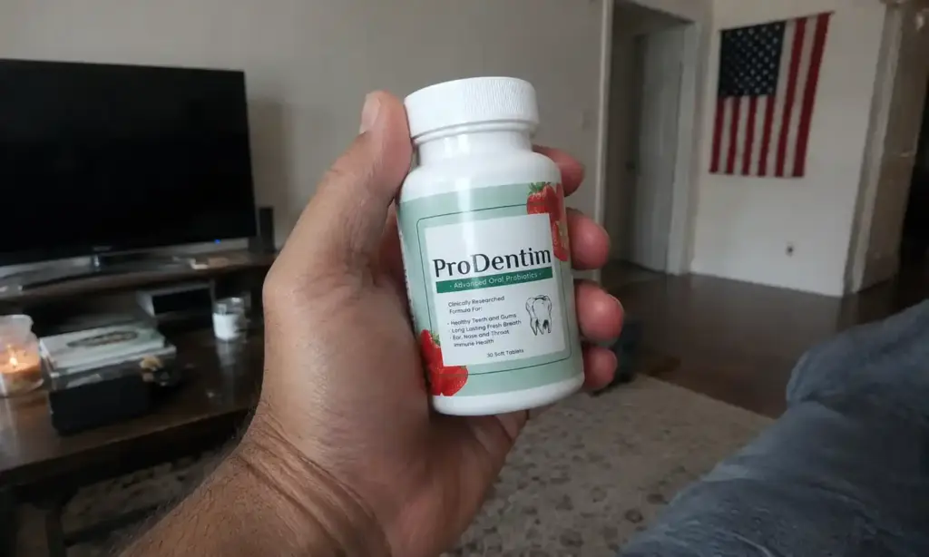 Hand holding ProDentim probiotic bottle