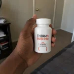 Hand holding Thermo Burn Pro capsules bottle.