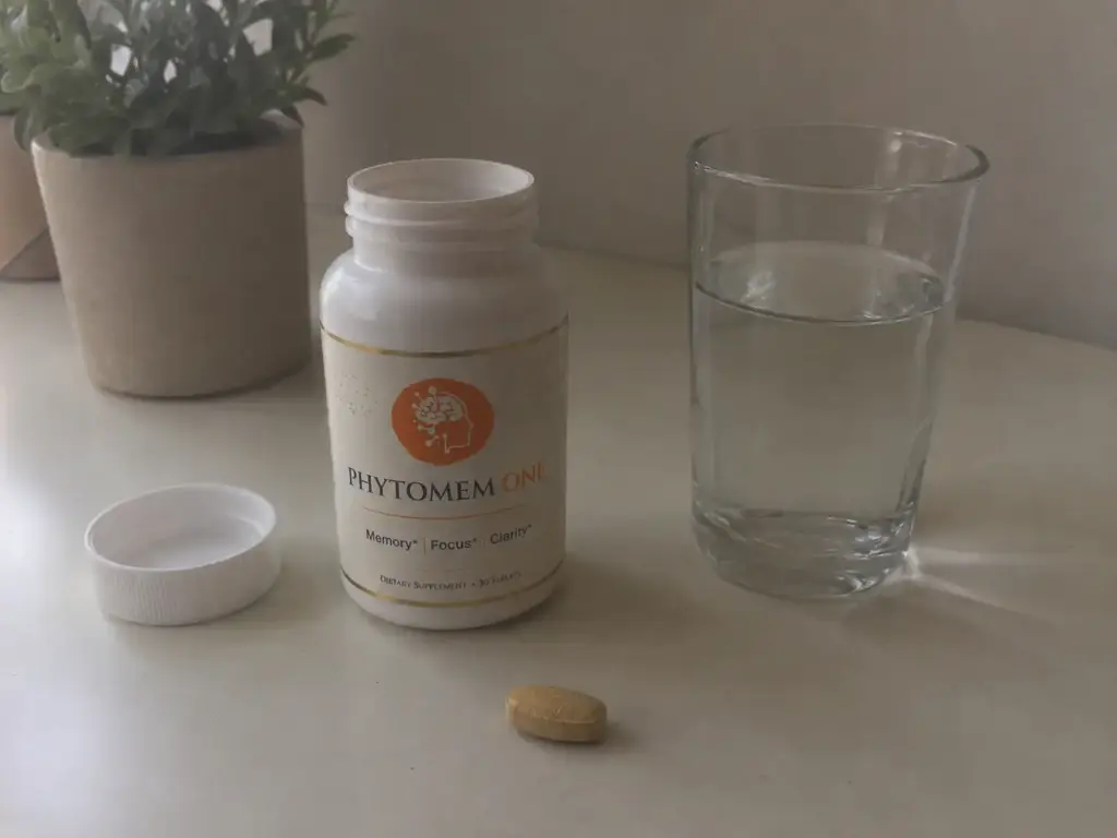 Opened Phytomem One bottle with one tablet and a glass of water